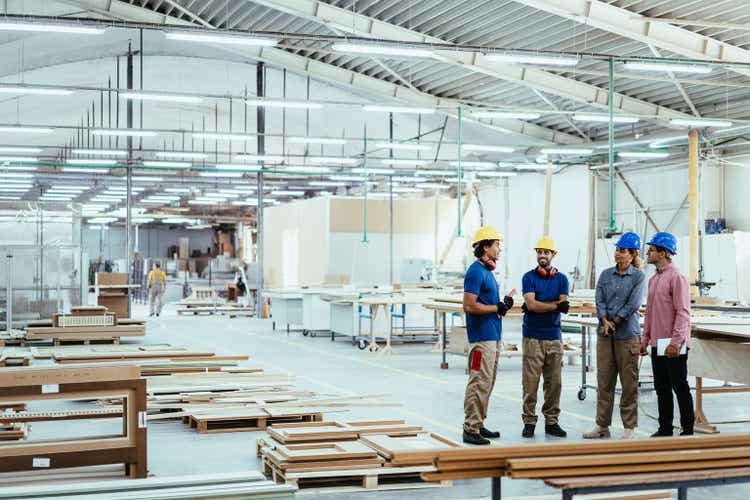 Architects, engineers and blue collar staff working together in modern factory