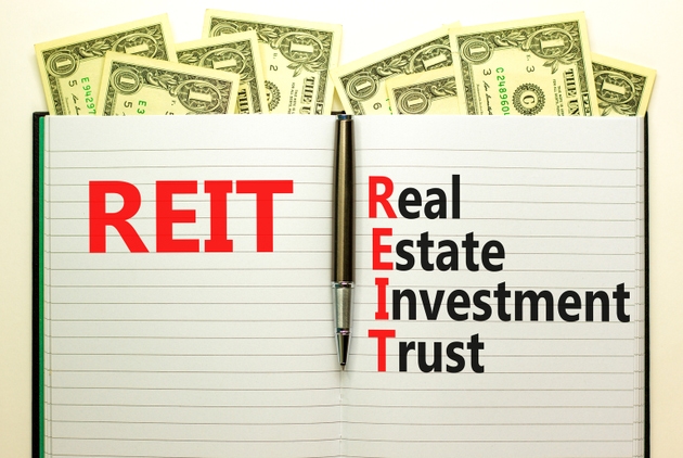 REIT real estate investment trust symbol. Concept words REIT real estate investment trust on book on beautiful white background. Dollar bills. Business REIT real estate investment trust concept.