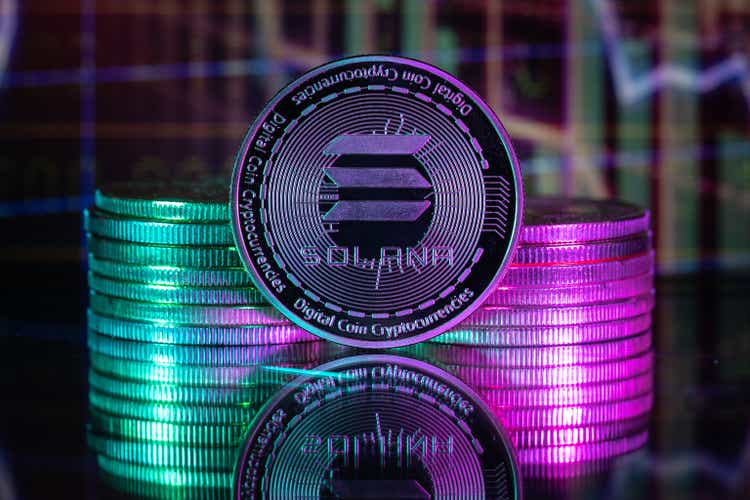 Solana SOL cryptocurrency physical coin and blurry price charts.