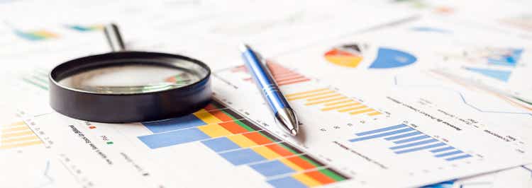 Magnifier and pen on charts graphs paper. Financial development. Banner