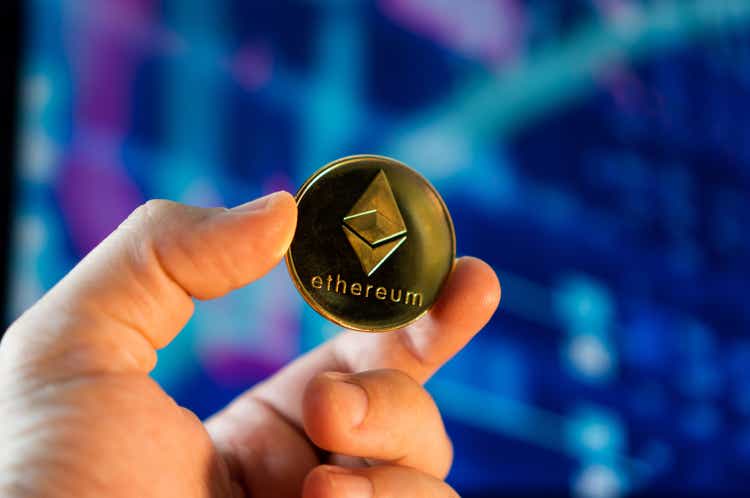 Man holding a golden Ethereum coin with the financial stock market graph in the background. Cryptocurrency coin. Financial market