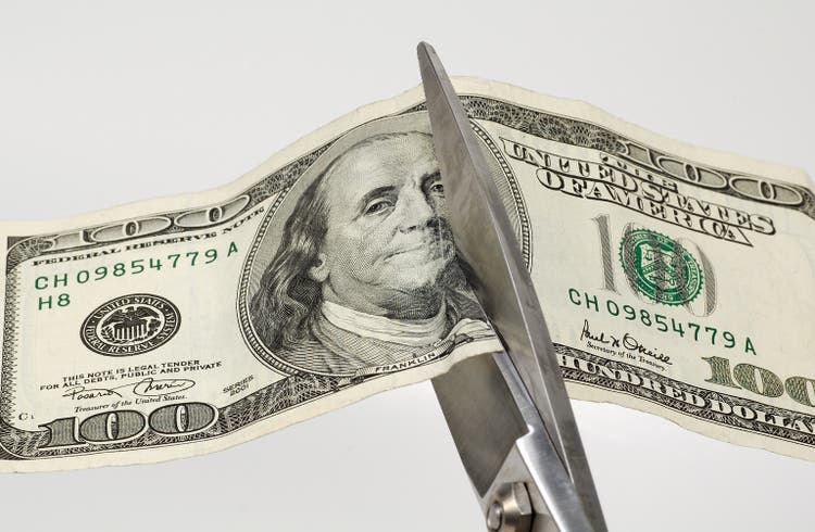 Symbolic photo of scissors cutting a hundred dollar bill