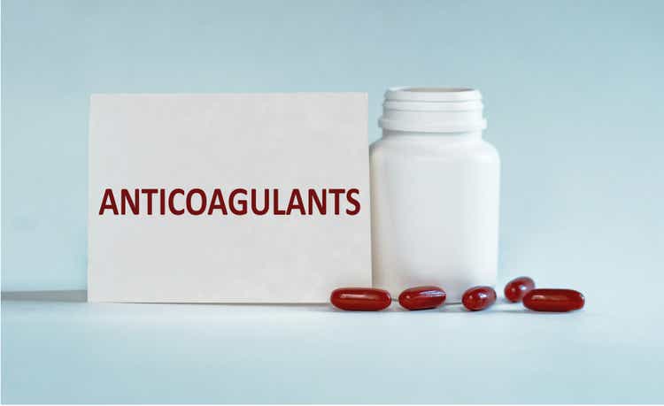 On a light blue background a card with the text ANTICOAGULANTS near the white bottle pills.