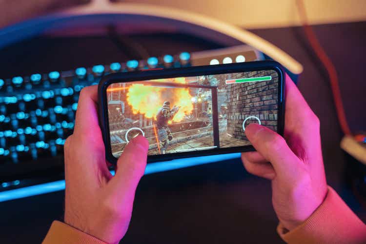 Hands of gamer playing mobile video games on his smartphone