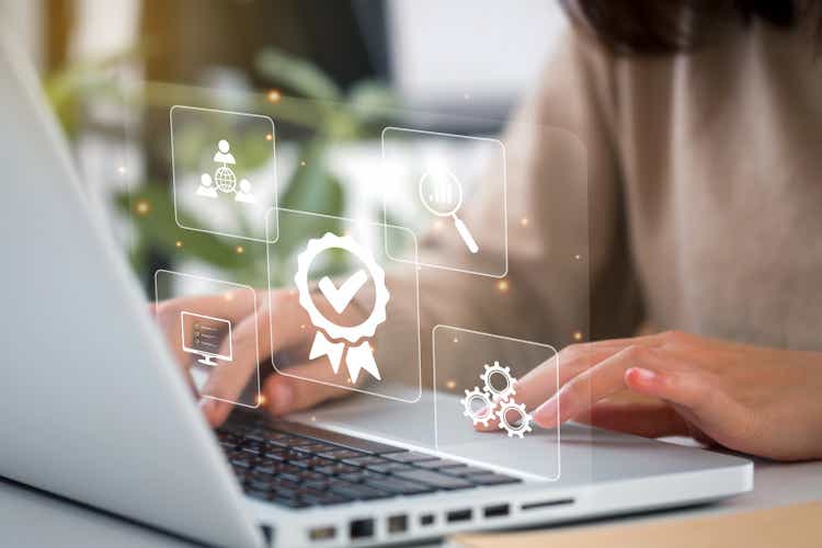 Businesswomen working on laptops with sign of the top service Quality control certification checked guarantees of the standard of company product. Concept on virtual screen.
