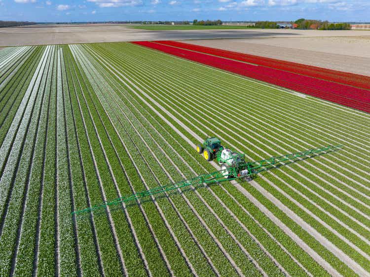 Tulips with a John Deere tractor hauling an agricultural crops sprayer in a field during a beautiful springtime day