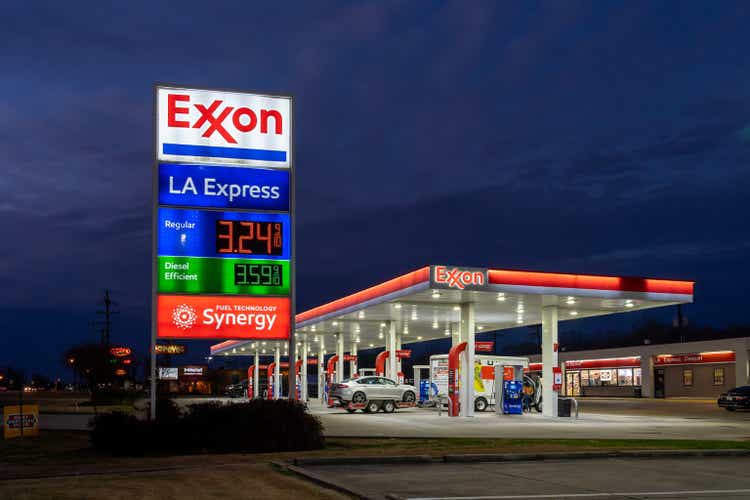 A Exxon gas station is seen with dark blue sky in the background at dusk.