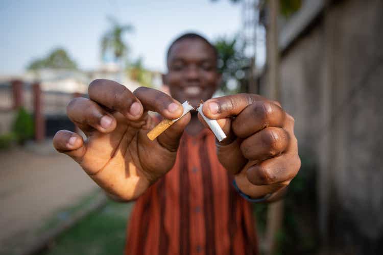 African boy breaks a cigarette in two, he does it for his own good, quit smoking concept