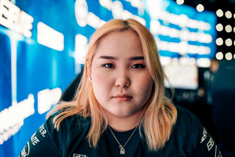 Portrait of blond female gamer with serious face at eSports arena