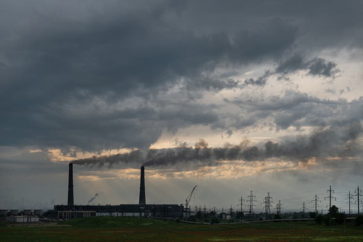 Pipes of coal-fired power plant and poppy field in spring