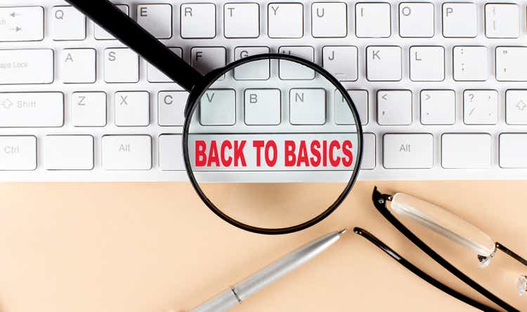 Text BACK TO BASICS on keboard with magnifier , glasses and pen on beige background