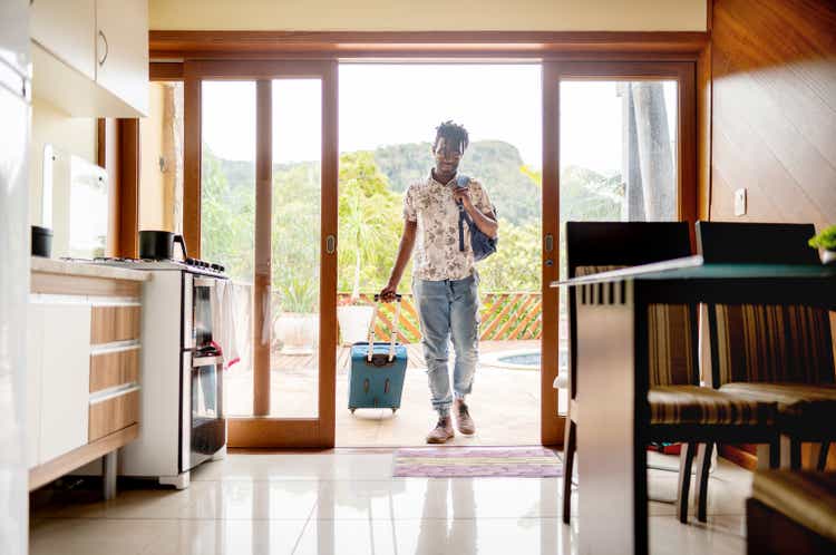 Man with a suitcase walking through the patio doors of his accommodation