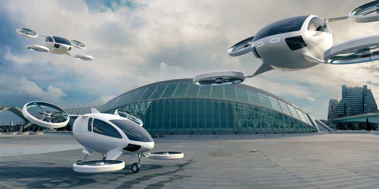 Three eVTOL aircraft parked and in full flight in front of the terminal building