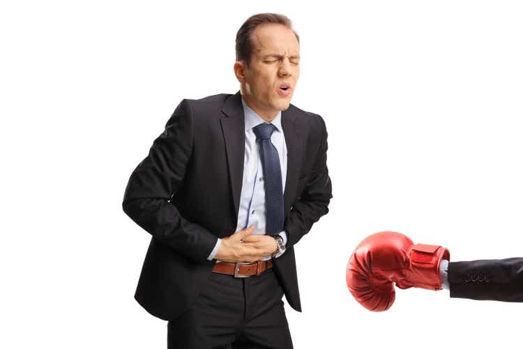 Boxing glove punching a businessman in the abdomen
