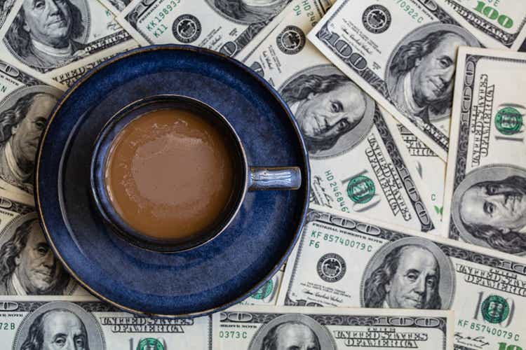 cup of coffee on 100 dollar banknotes background