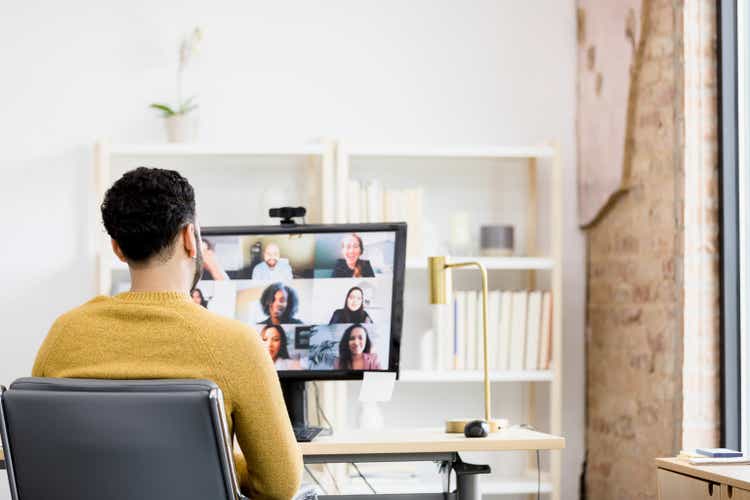 Over-the-shoulder view unrecognizable man using desktop PC for meeting