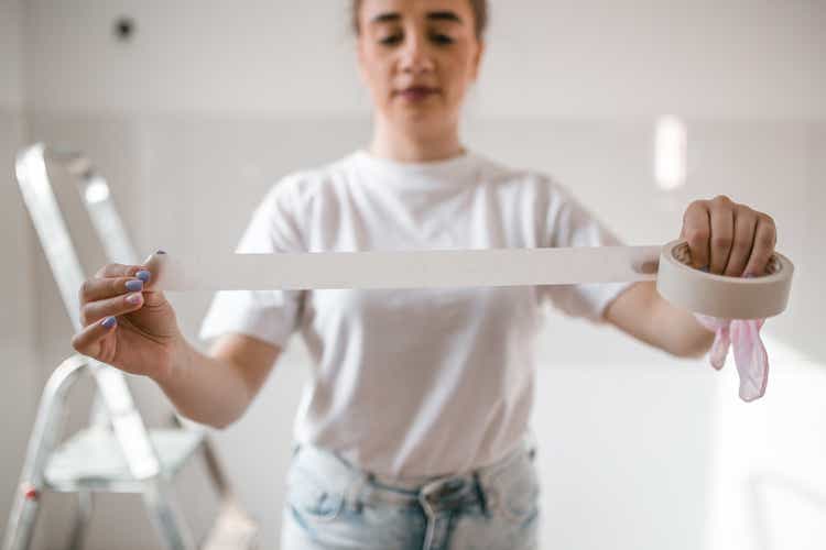 A woman in a white T-shirt holding a duct tape in her hands