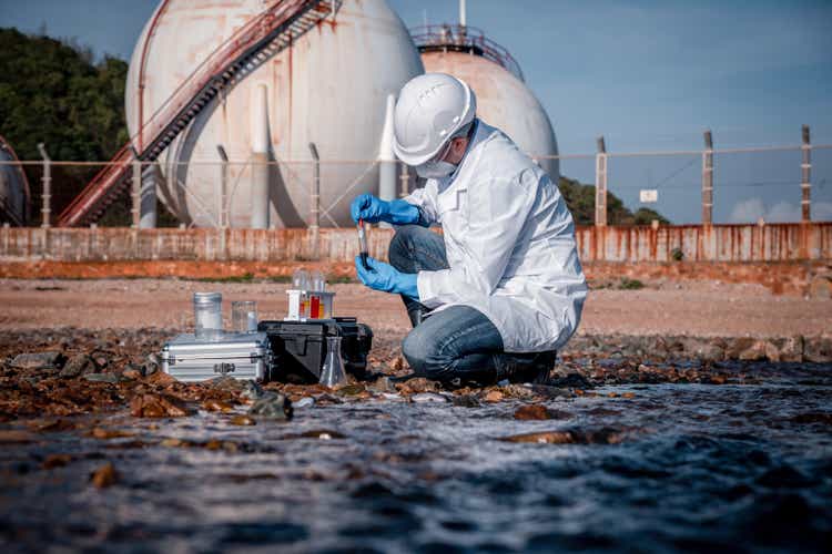 Scientist wearing safety uniform and glove under working water analysis and water quality by get waste water to check case in laboratory is environment pollution problem concept.