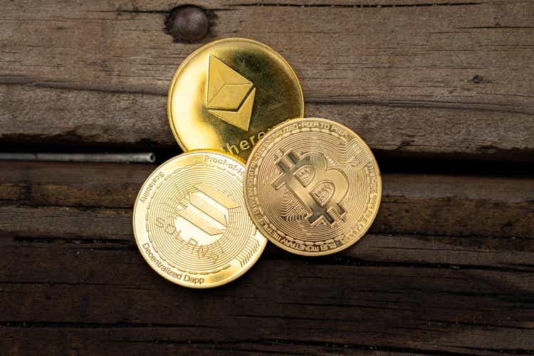 Closeup of golden Bitcoin, Ethereum and Solana coins on a rustic wooden table. Cryptocurrency currency. Financial market. Selective focus