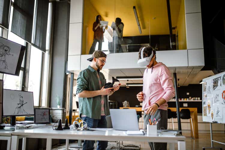 Group of coworkers testing VR simulator in the office