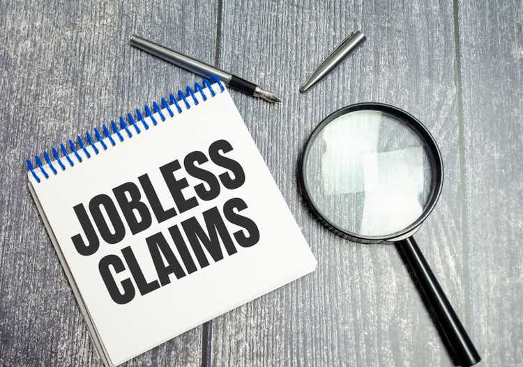 Jobless claims text on white paper from a notepad on a wooden background.