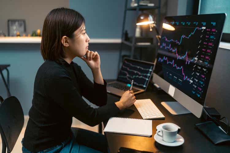 Young woman doing cryptocurrency business transaction on computer at home at night