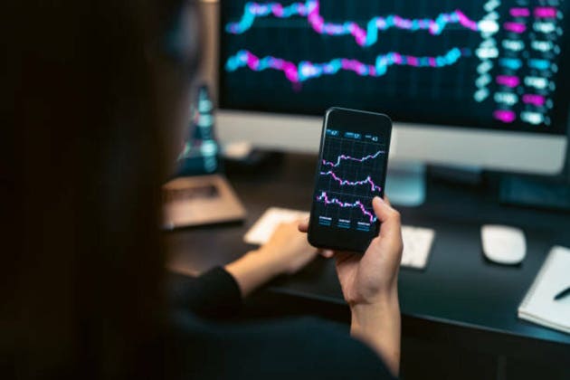 Young woman doing cryptocurrency business trading on her computer at home at nigh