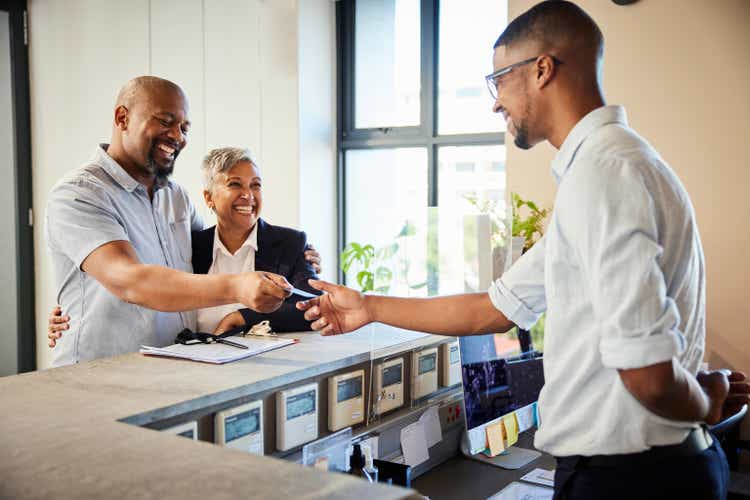 Smiling mature couple giving hotel reception their cardkey