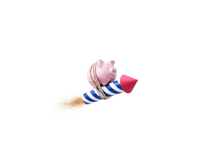 Concept still life image with piggy bank tied to a rocket on white