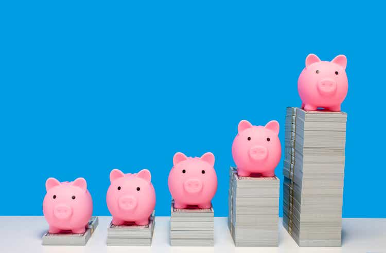 Pink piggy banks on ascending stacks of paper currency