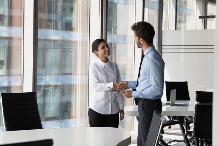 Two diverse confident business man and woman shaking hands