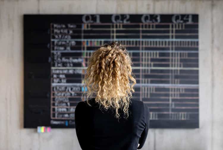 Business woman looking at the project management calendar in her office