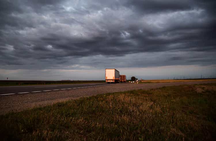 A column of trucks with trailers carry cargo in the evening against a cloudy sky with clouds. Direct FTL transportation model. Copy space for text, expedited shipping