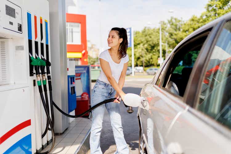 Smiling woman refueling the gas tank at fuel pump