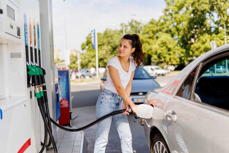 Upset woman refueling the gas tank at fuel pump