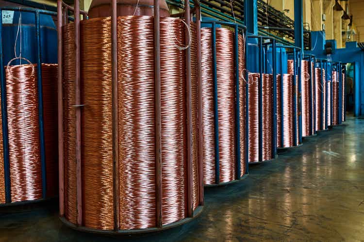 Coiling shiny copper cable onto reels to package at plant