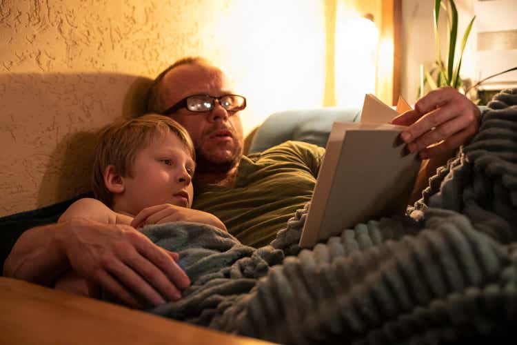 father reading a book to son