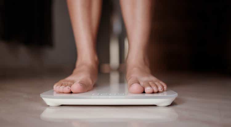 Woman on scales measure weight. Female dieting checking BMI weight loss.