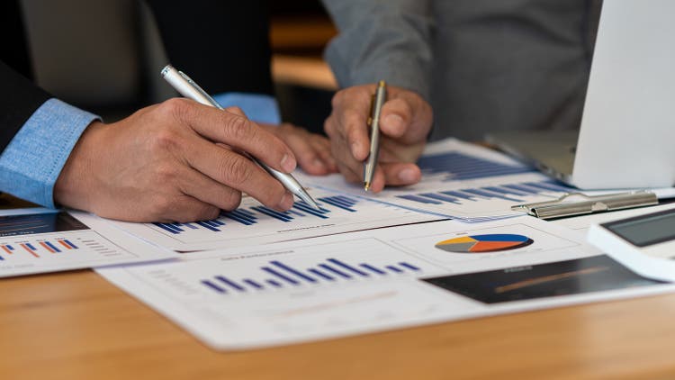 business people meet with design ideas business planning Picture of two young businessmen holding pens and graph papers at a meeting discussing charts and graphs showing successful teamwork.