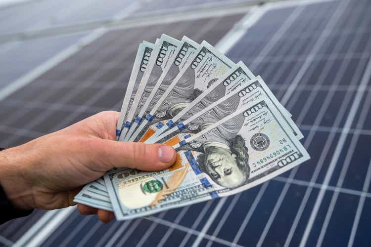 beautiful young gorgeous worker hands holding round sum of money for installing solar panels.