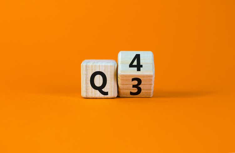From 3rd to 4th quarter symbol. Turned a wooden cube and changed words "Q3" to "Q4". Beautiful orange table, orange background. Business, happy 4th quarter Q4 concept, copy space.