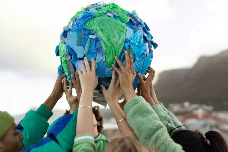 Group of teenagers holding up a world made of plastic trash
