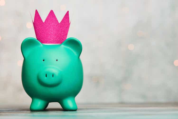 Cute green piggy bank wearing a pink crown in a bright setting