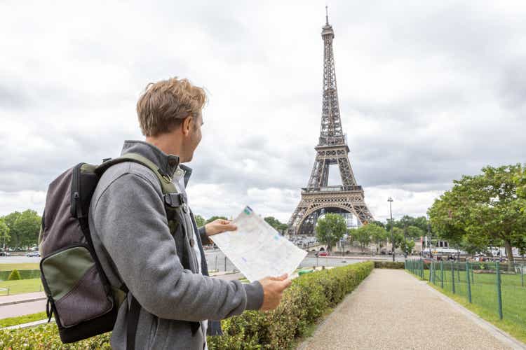 Young man in Paris near the Eiffel Tower looks at city map