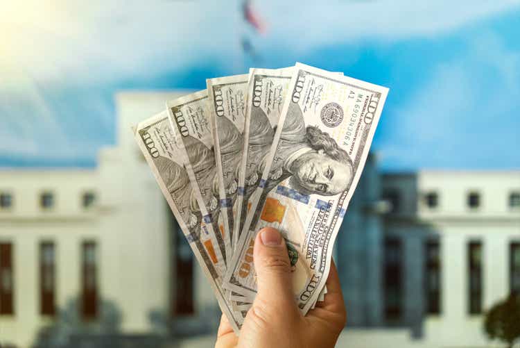 dollars in a man"s hand on background Federal Reserve Building in Washington DC, United States, FED