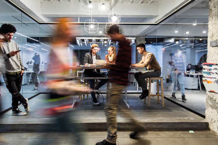Young creative people working in the office among people in blurred motion.