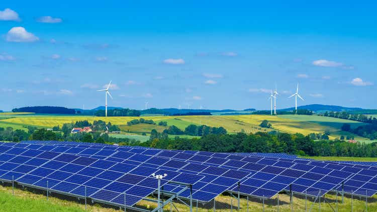 Wind turbines and solar panels in hilly rural area producing green energy