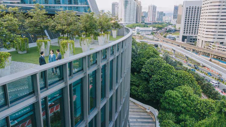 Drone point of view business person talking on roof garden outside office building