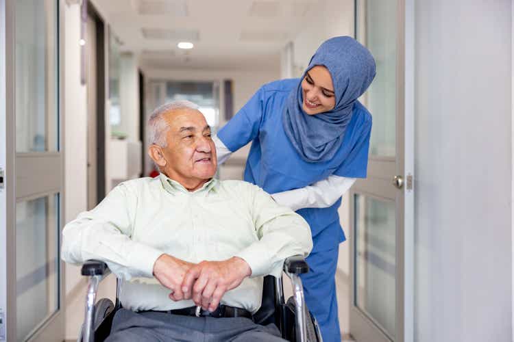 Muslim nurse taking care of a senior patient in a wheelchair