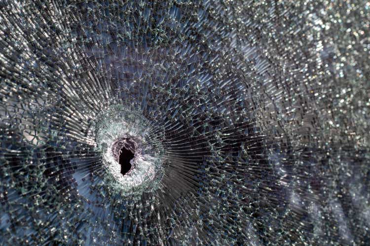 Holes on the windshield of the car, it was shot from a firearm. Bullet holes. Smash car windshield, broken and damaged car. The bullet made a cracked hole in the glass.